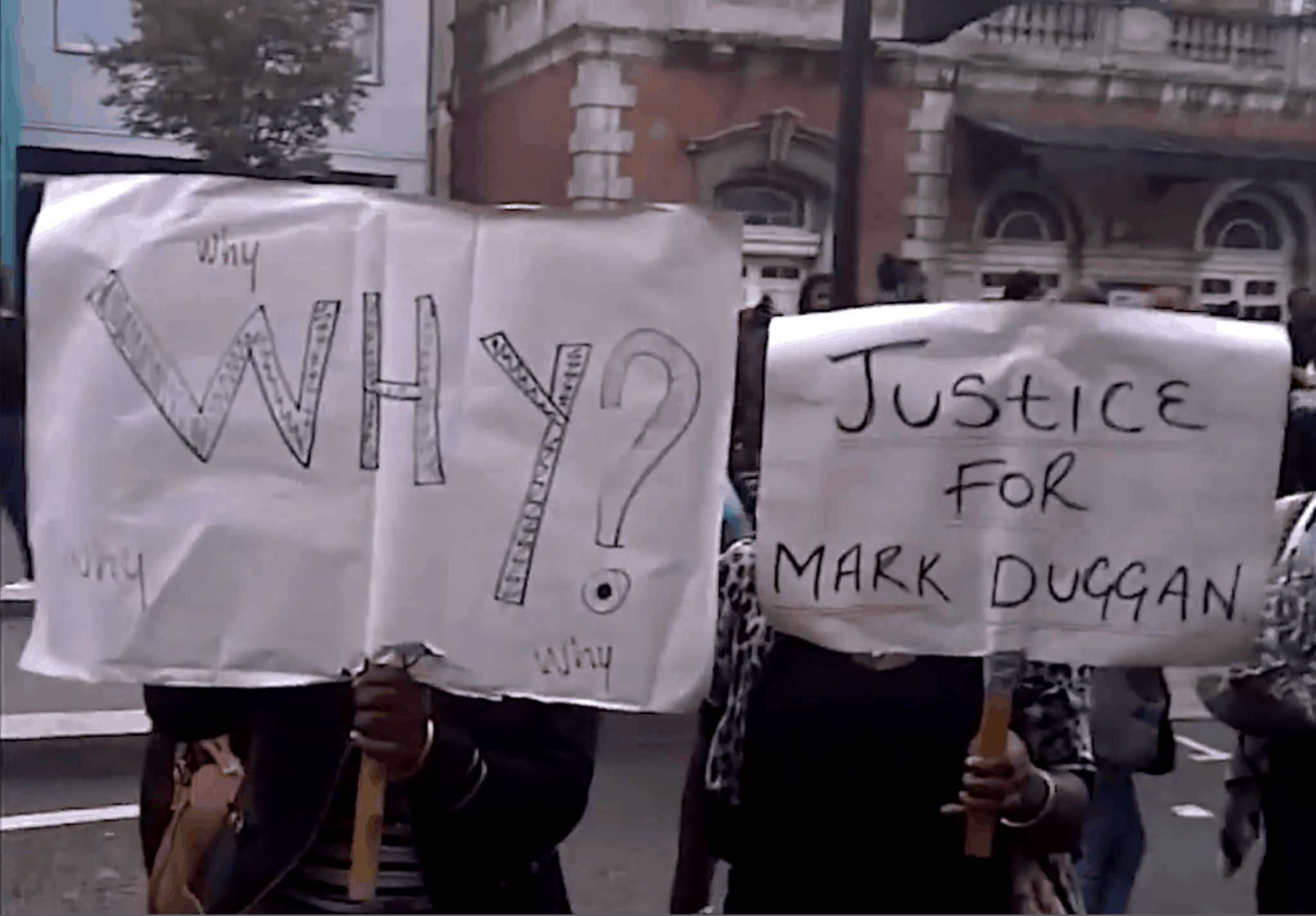 Protest – 1 - On 6 August 2011, protesters hold placards outside Tottenham Police Station. (BBC) Not for reproduction.