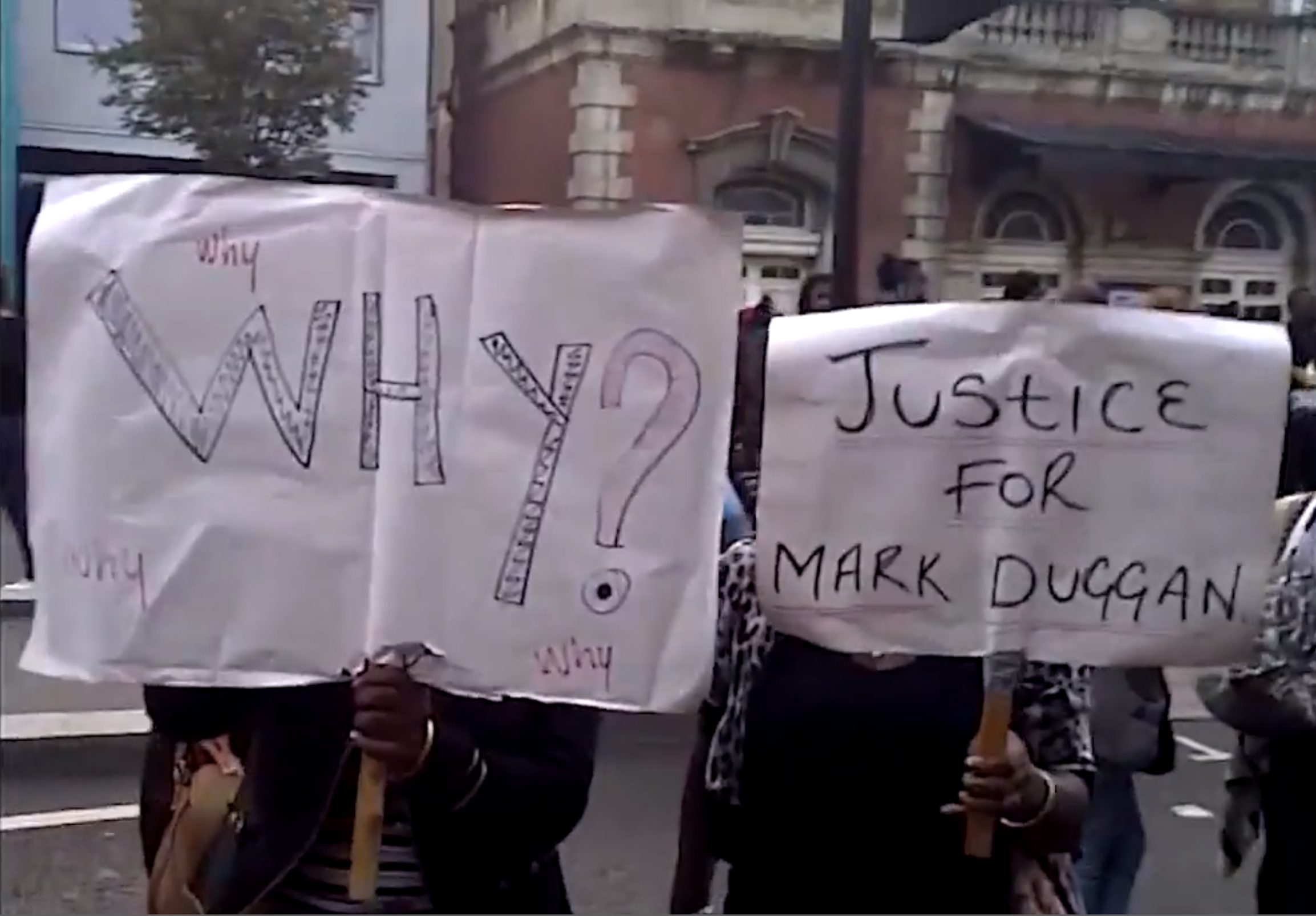 Protest – 1 - On 6 August 2011, protesters hold placards outside Tottenham Police Station. (BBC) Not for reproduction.