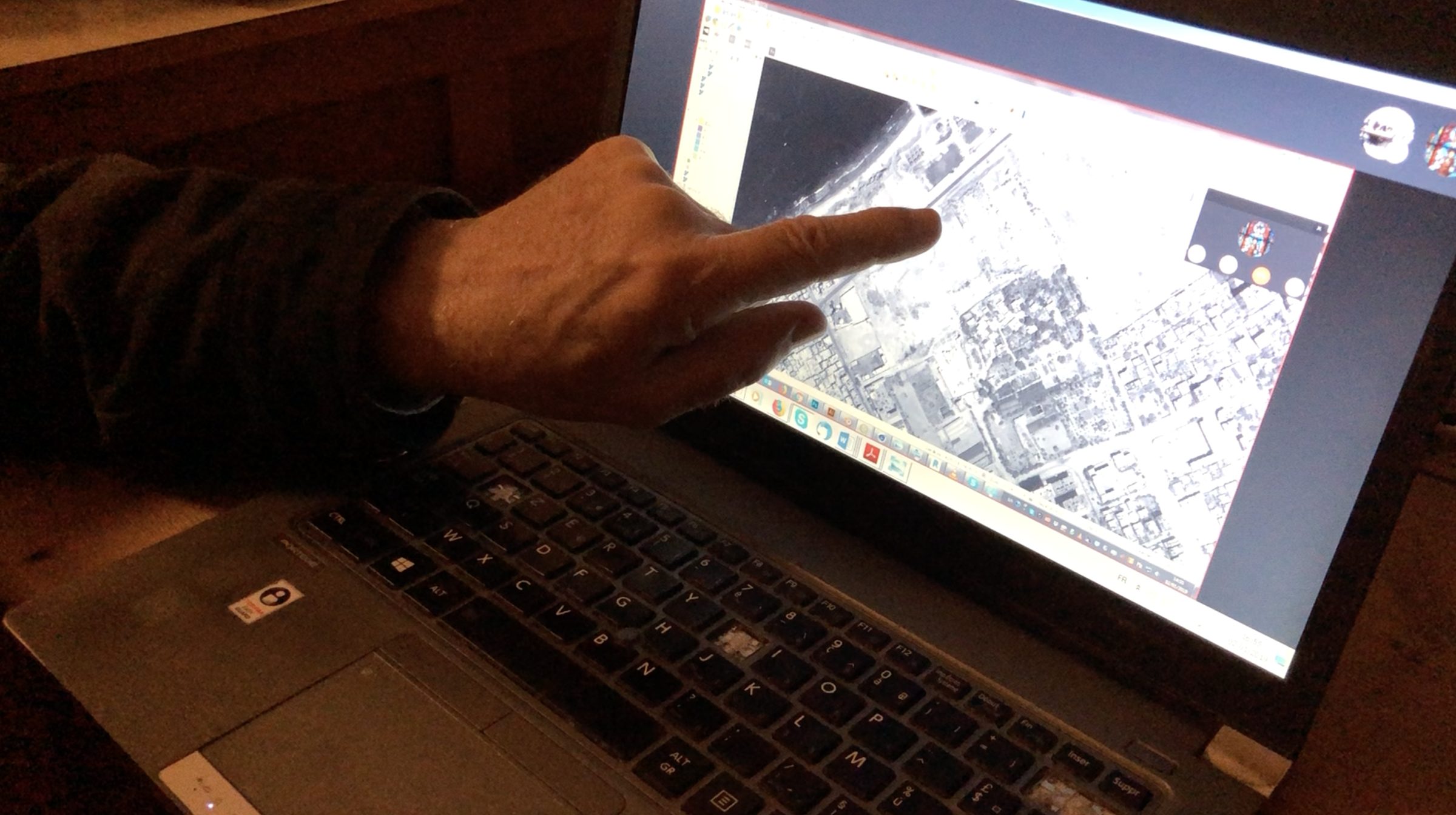  - Fig. 12: Jean-Baptiste Humbert, in his office at the École Biblique et Archéologique Française de Jérusalem, pointing to the location of the archaeological site within a satellite image. (Forensic Architecture, 2022)
